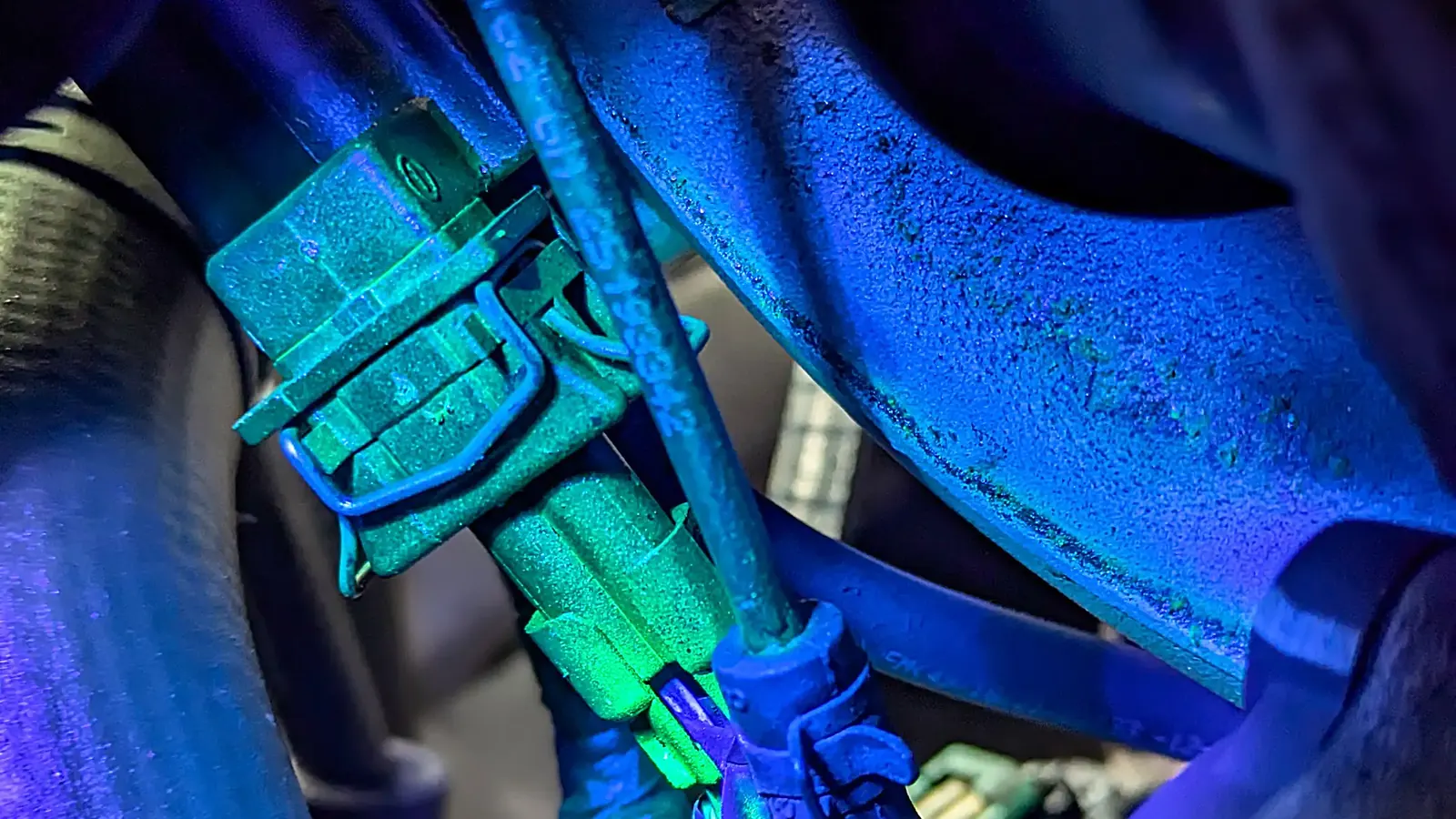 UV dye glowing at AC line fittings during a refrigerant leak search