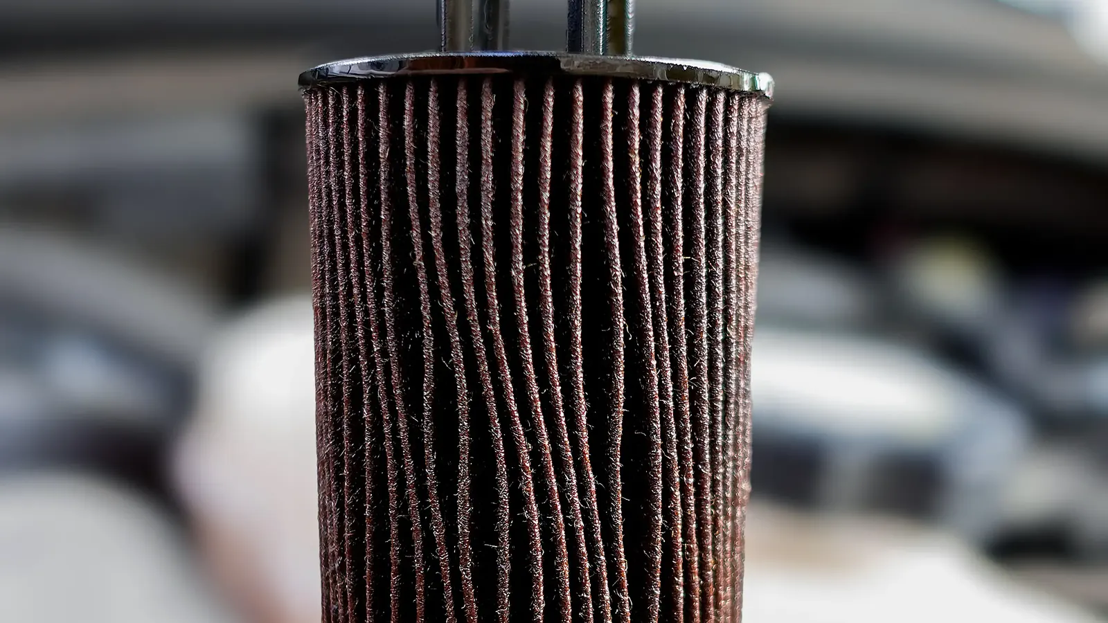 Used cartridge oil filter element held up over the engine bay during a mobile oil change